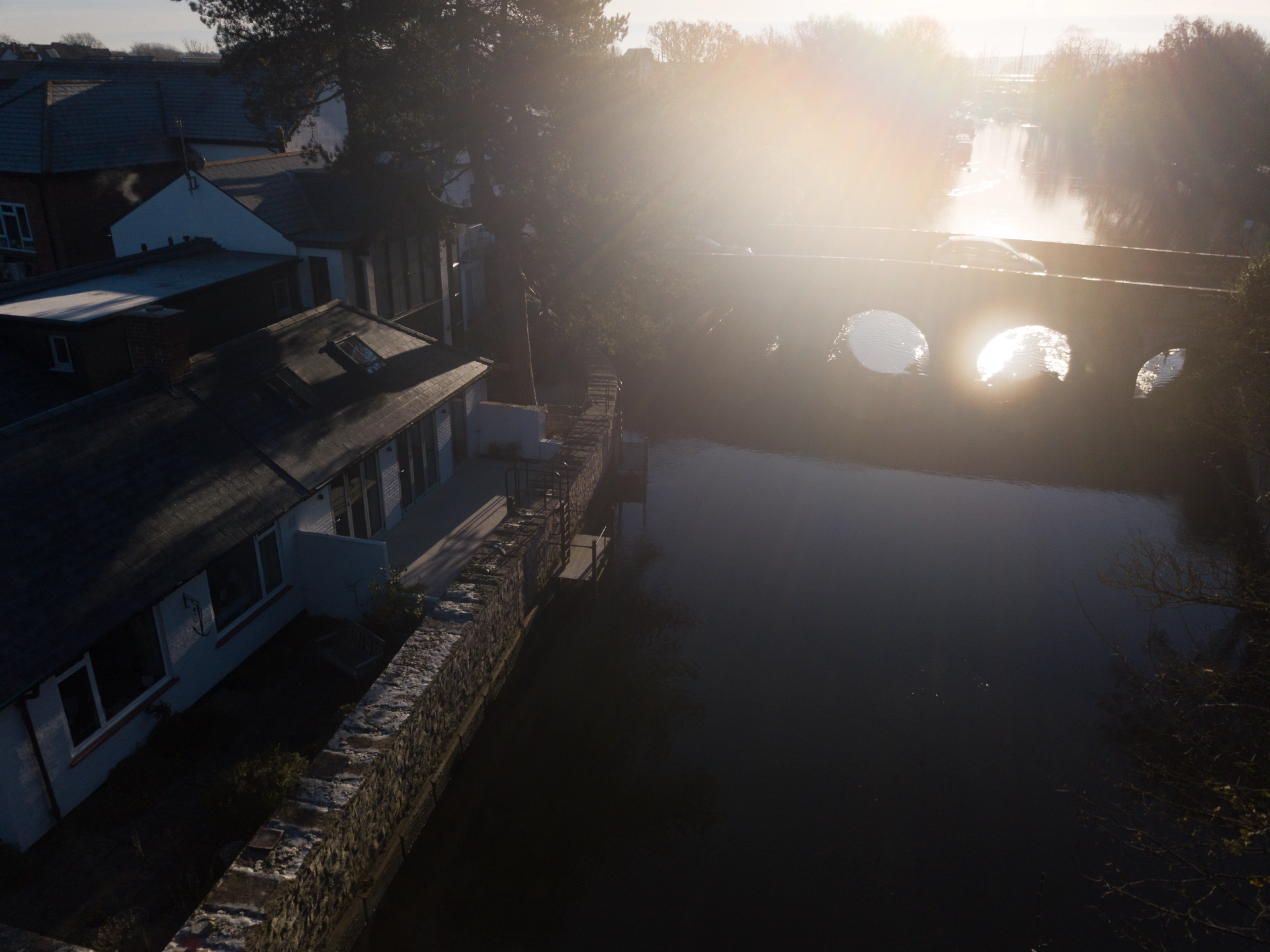 Drone shot of a beautiful riverside house with a bridge